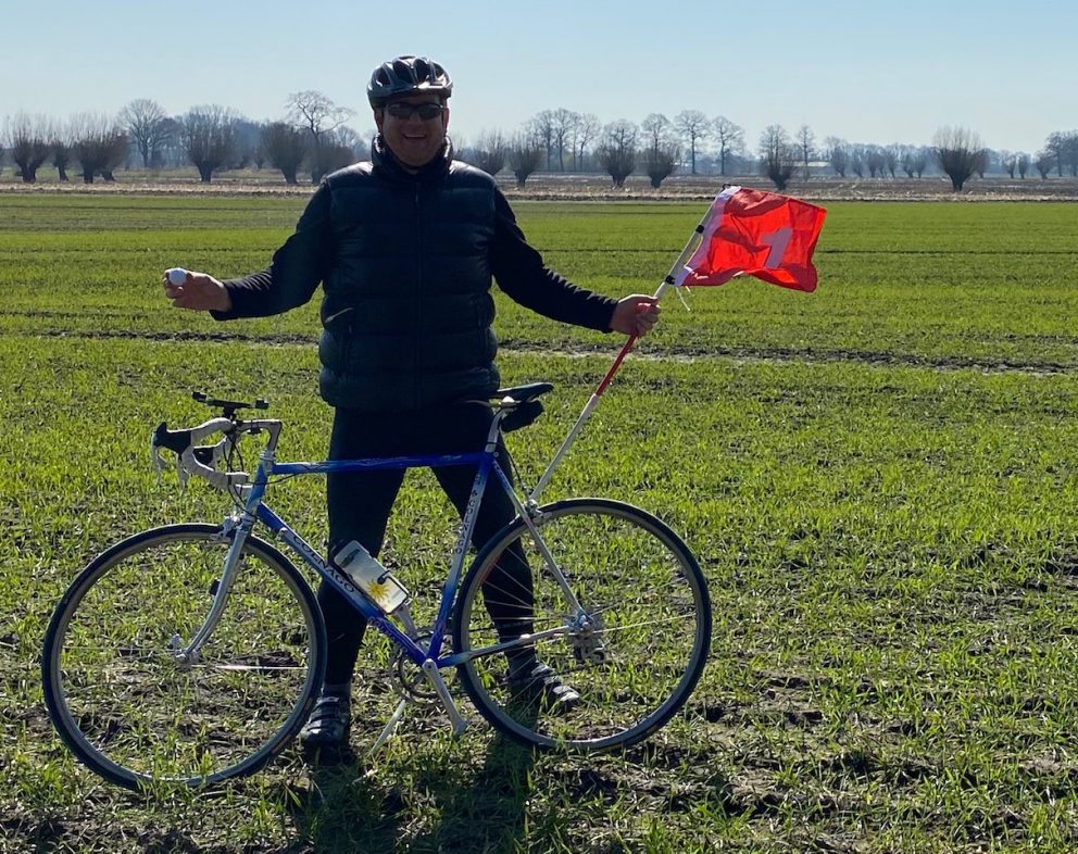 Dirk mit Rennrad und Fahne im Acker